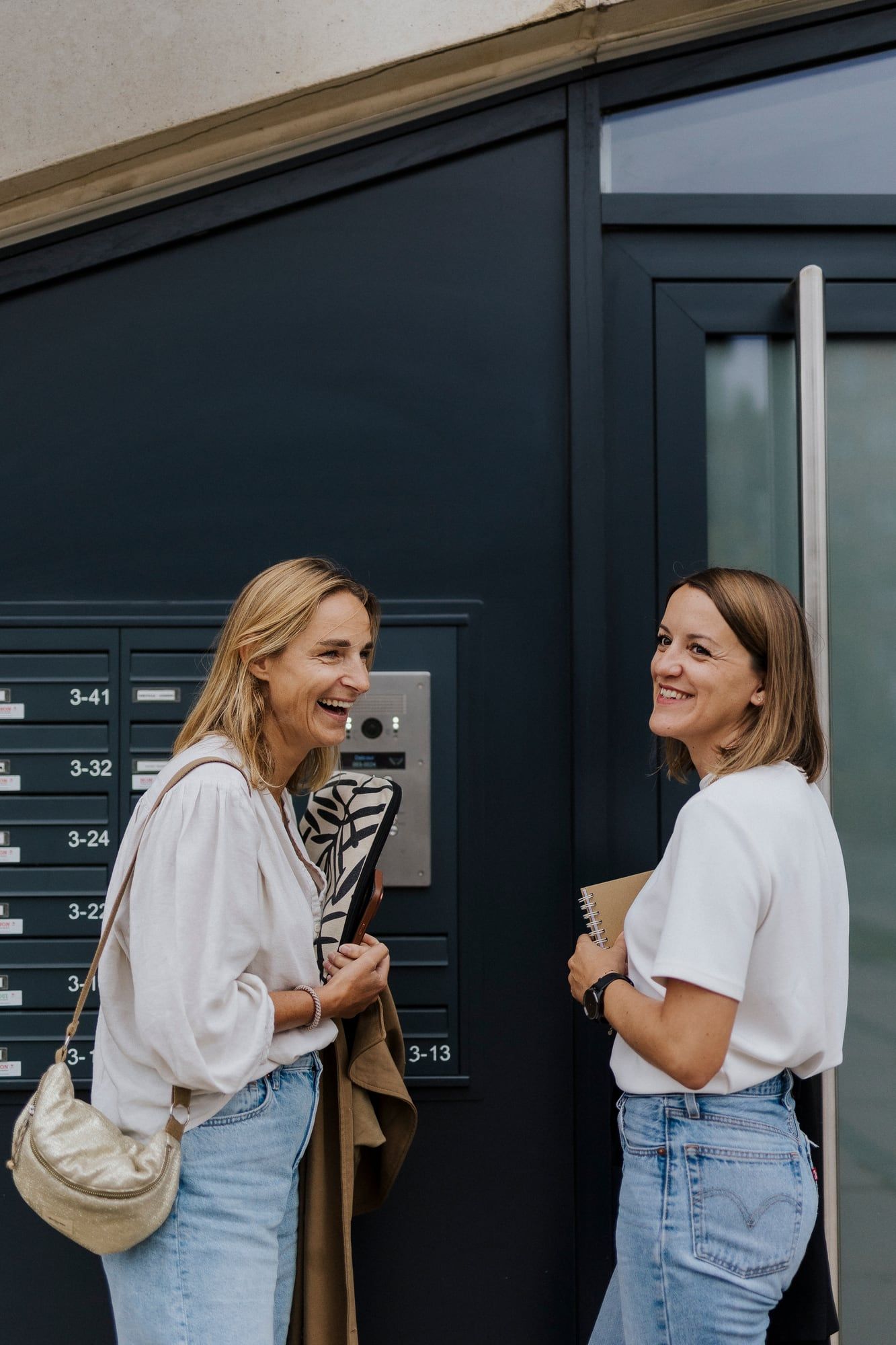 Deux membres de l’équipe ZE AGENCY échangent devant une porte d’entrée